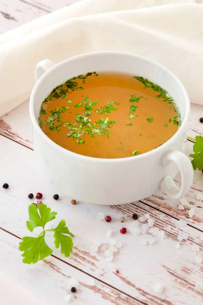 Cooked hot bone broth with spices and fresh herbs. stock photo