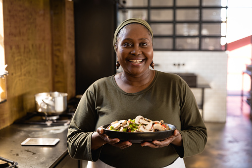 Front view of an Senior African woman at a cookery class, holding a bowl filled with vegetables. Active Seniors enjoying their retirement.