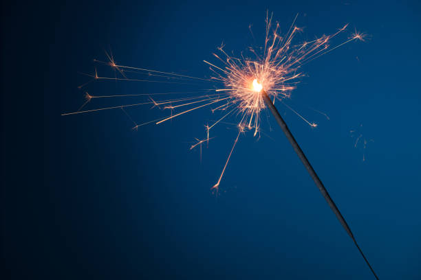 istock Burning festive Christmas sparkler on blue background 1204636605