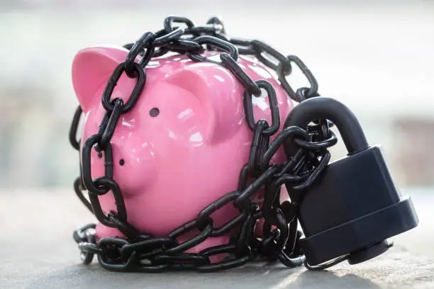 Piggy bank savings secured with padlock chained up and locked