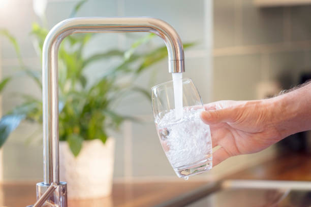 Filling up a glass with drinking water from kitchen tap Filling up a glass with clean drinking water from kitchen faucet faucet stock pictures, royalty-free photos & images