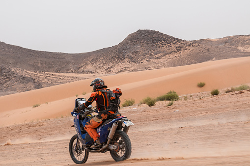 Merzouga, Morocco - march 21, 2012: Biker driving along the desert dunes of Erg Chebbi