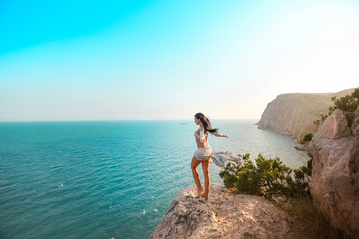 Woman outdors at the top of the mountain. Girl traveller in a dress with a high slit