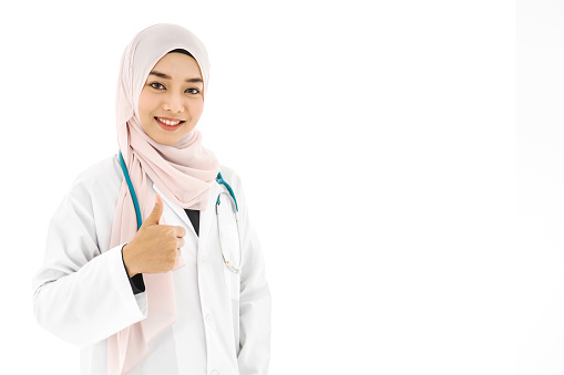 Portrait of beautiful asian muslim woman doctor smiling cheerful with thumbs up gesture isolated over white background