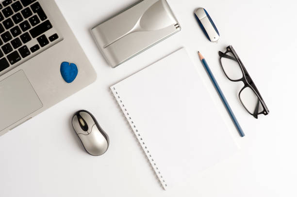 istock Office desk or executive desk with laptop, white sheet book, glasses, external hard drive, computer mouse and memory (USB), digital clock, top / plane view 1204640053