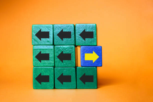 istock Wooden block with yellow arrow facing the opposite direction black arrows, Unique, think different, individual and standing out from the crowd concept. 1204640942