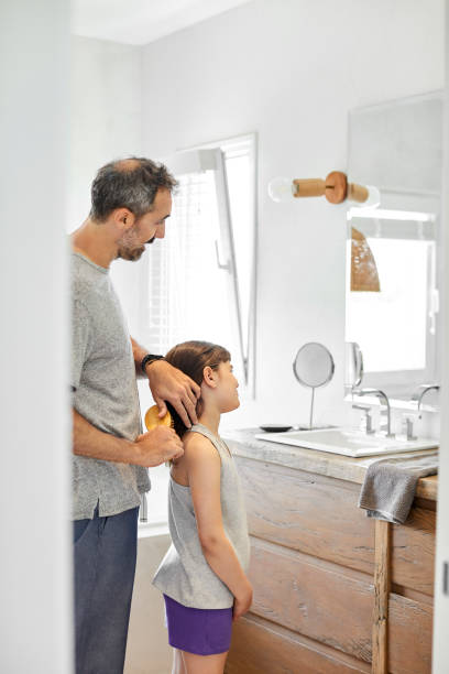 istock Gay father brushing daughter's hair in bathroom 1204641148