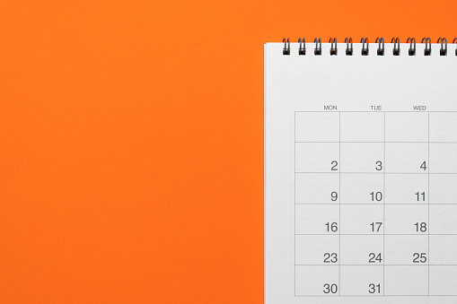 close up of calendar on the orange table background, planning for business meeting or travel planning concept