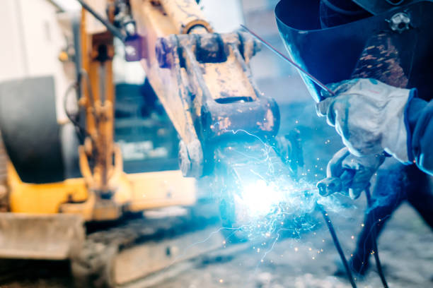 istock mechanic, welder on construction site. Repair welding is done on indsutrial machinery 1204643863