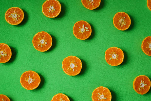istock Cut fresh oranges on red plate and green background 1204644886