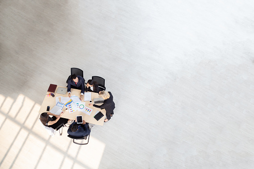 Top view of group of multiethnic busy people working in an office, Aerial view with businessman and businesswoman sitting around a conference table with blank copy space, Business meeting concept
