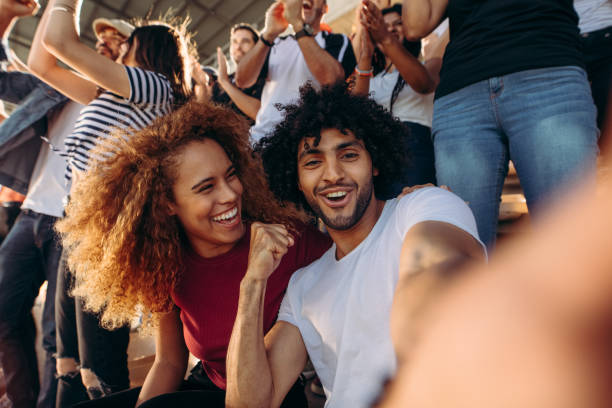 istock Couple of spectators taking selfie in stadium 1204651446