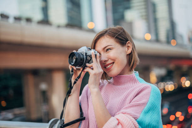 istock Beautiful lady taking pictures with camera in city 1204654921