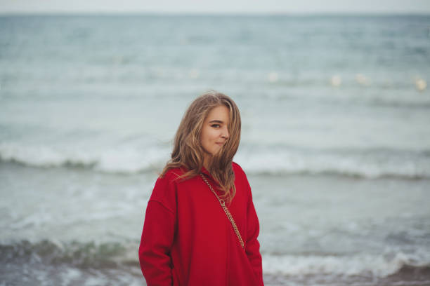 istock Beautiful woman in red coat walking on the beach 1204656566
