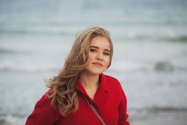 istock Beautiful woman in red coat walking on the beach 1204656578