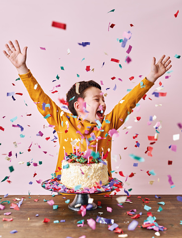 istock Cute child on pink background with cake and party confetti. Birthday party and big celebration. 1204656827