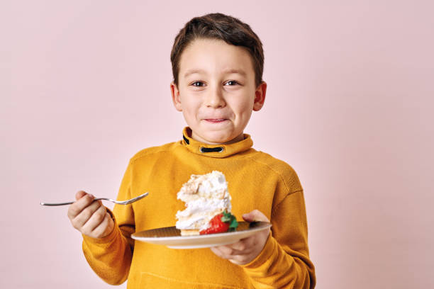 istock Cute child eating cake on pink background. 1204658763