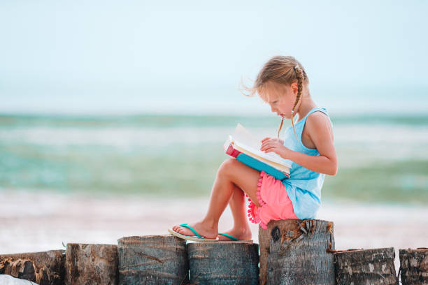Little girl reading book on the beach
