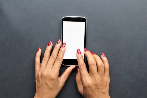 Black smartphone on the ground women hands red nail polish using the phone  in position writing message photo isolate on black background top view copy space