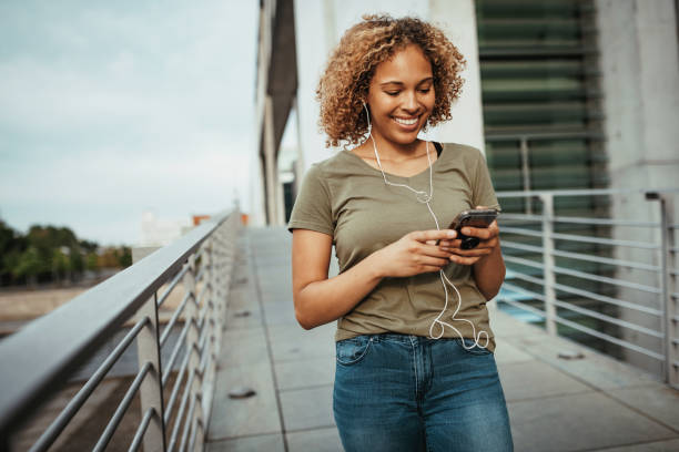 istock Cheerful curly mixed race woman with smart phone 1204661376
