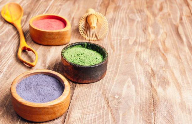 日本の抹茶の異なる色:木製の背景に木製のボウルに緑、赤、青。アサイベリーパウダー、緑茶葉パウダー、クリトリアフラワーパウダー。選択的焦点