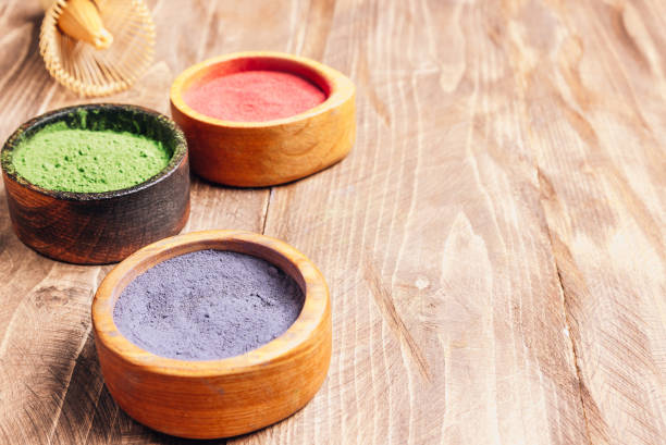 日本の抹茶の異なる色:木製の背景に木製のボウルに緑、赤、青。アサイベリーパウダー、緑茶葉パウダー、クリトリアフラワーパウダー。選択的焦点