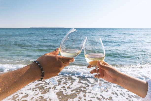 istock Two hands with glasses of wine on the beach. Summer vacations concept. 1204668752