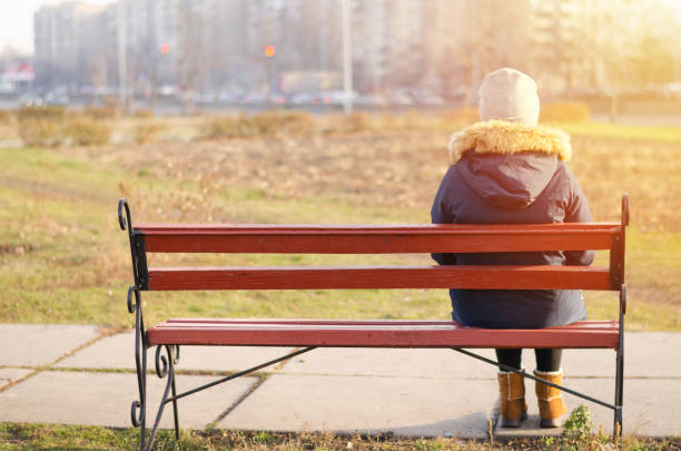 istock Girl in autumn clothes sits alone on a bench. 1204668913