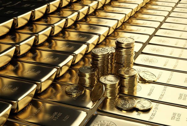 sztabki sztabki złota ułożone w dół z niektórych stosów złotych monet dolara. - gold ingot coin bullion zdjęcia i obrazy z banku zdjęć