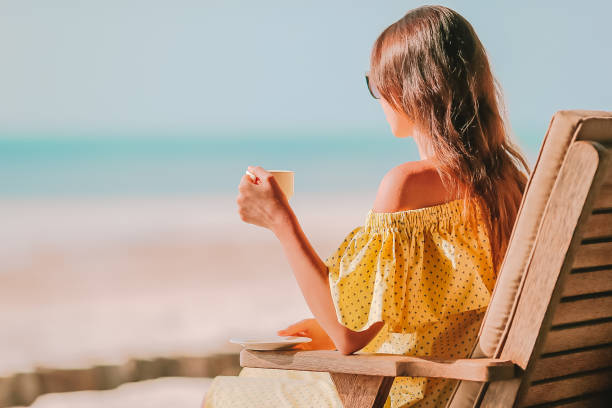 istock Young woman with hot coffee enjoying beach view 1204673144