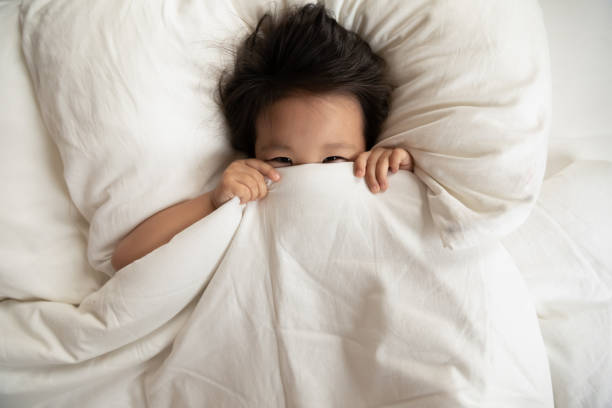 istock Happy little Asian girl hide under blanket in bed 1204673216