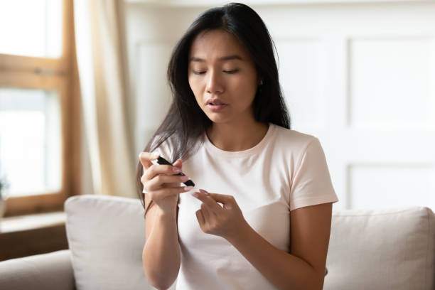 la femme asiatique mesurent le niveau de sucre de sang avec le glucometer - insulin diabetes pen injecting photos et images de collection