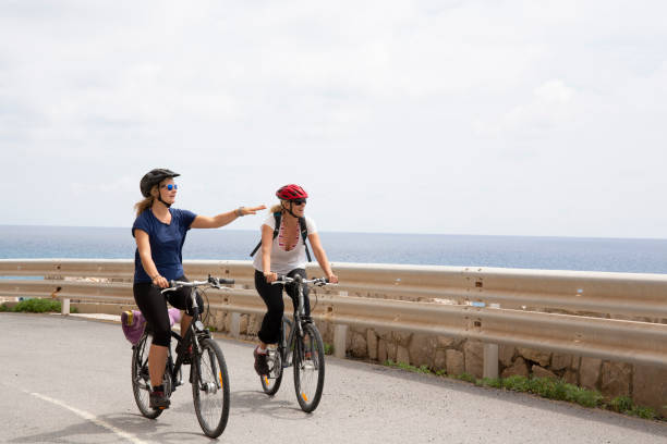 mom and daughter pedal bikes along empty coastal road - 2127 imagens e fotografias de stock