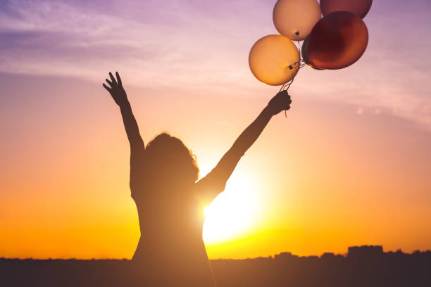 istock Happy woman with balloons at sunset 1204675567
