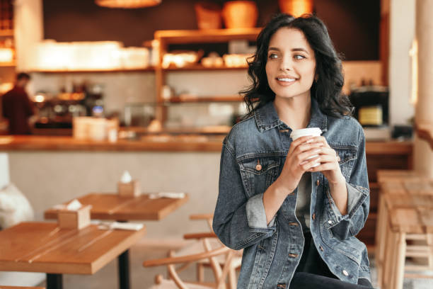 istock Positive casual woman drinking coffee alone at cafe 1204675782