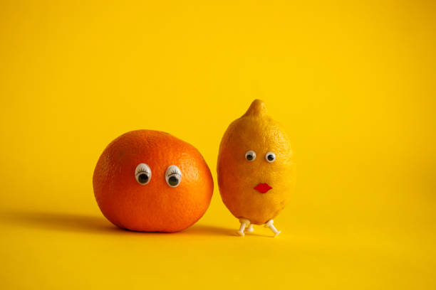istock Orange and lemon with funny faces on yellow background 1204676730