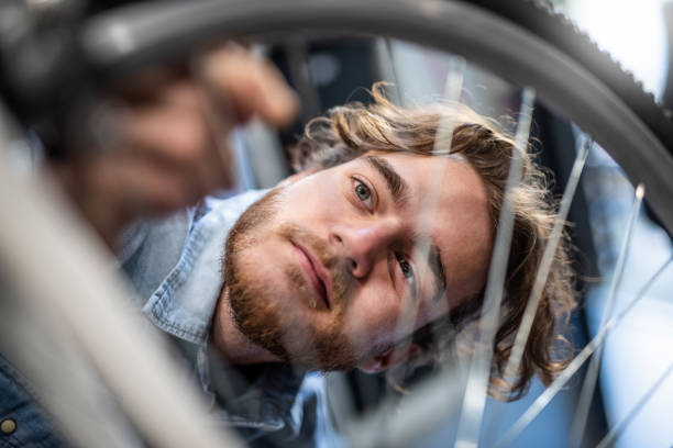 young mechanic examining a bent bicycle wheel. - bicycle wheel tire spoke imagens e fotografias de stock