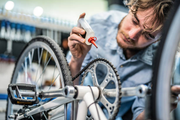 Mechanic repairing bicycle breaks in workshop Mechanic repairing bicycle breaks in workshop lubrication stock pictures, royalty-free photos & images
