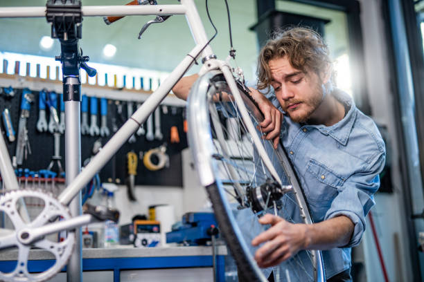 istock Young mechanic examining a bent bicycle wheel. 1204684726