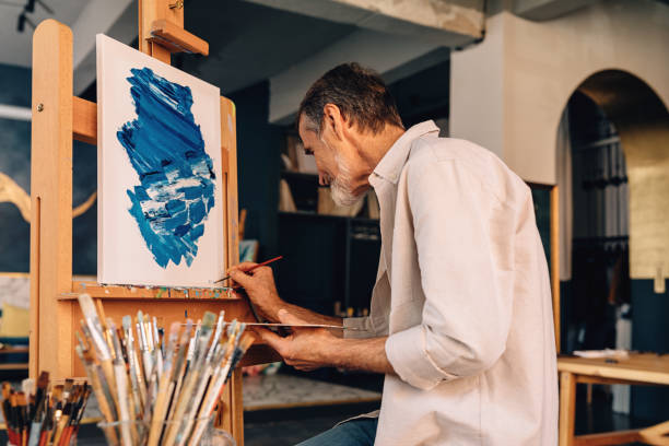istock Man painter drawing on canvas. Male artist in studio. 1204687315