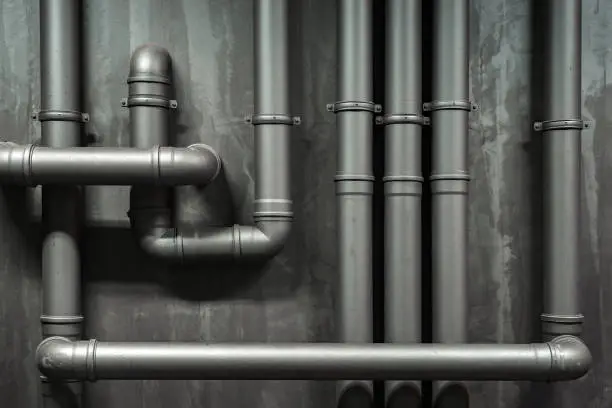 Photo of Close up of a wall with pipes. Metallic tubes wall texture. Black barrel and tubing - concept. Silver pipeline system. Tubing concept. Difficult communication, retro, texture a lot of pipes