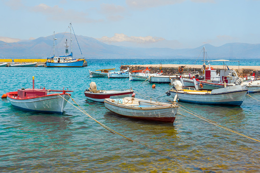 Fishing boats on mountains background. Empty fishing boats near coastline. Seascape with boats on mountain range background. Supply vessel at the central fish market in Euboea, Greece