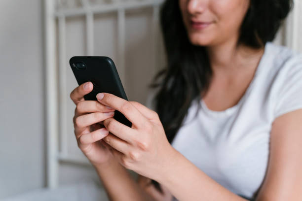 istock unrecognizable caucasian woman on bed using mobile phone. Daytime and technology concept. Lifestyle indoors 1204696125