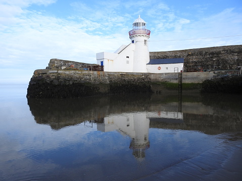 Balbriggan pier with lighthouse reflected in the sea.