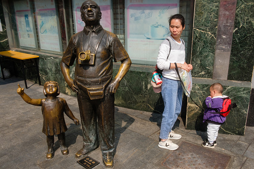 Guangzhou, China - February 22, 2019: Mother and child stand by father and child statue at Guangzhou’s Shangxiajiu Pedestrian Street.