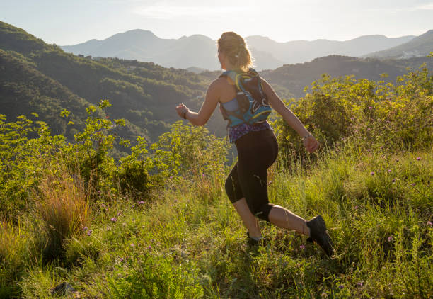 istock Female trail runner traverses grassy ridge at sunrise 1204699749