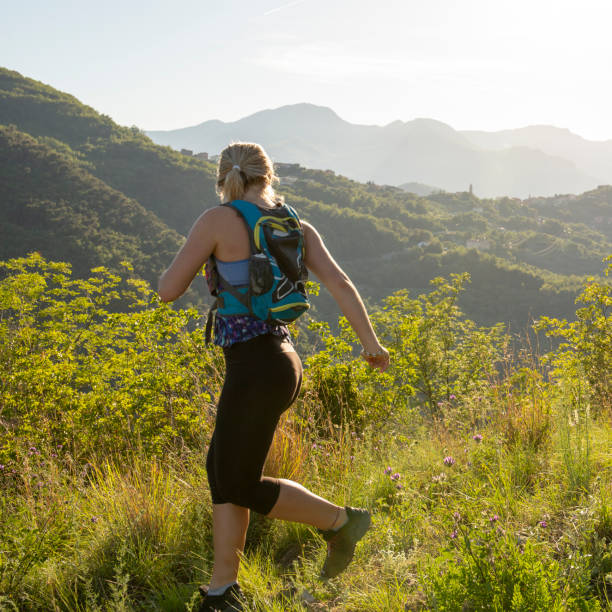 istock Female trail runner traverses grassy ridge at sunrise 1204699989