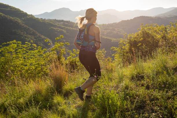 istock Female trail runner traverses grassy ridge at sunrise 1204699990