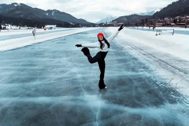 Amateur female ice skater making figures and having fun on the ice lake.