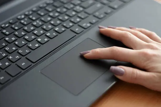 Photo of Female using black laptop for working. surfing internet using touchpad. business concept.